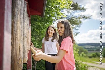 Nahaufnahme eines spielenden Mädchens an der Klangstation. Zweites Mädchen im Hintergrund